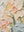 A close-up of a hand-painted floral oil painting with thick 3D impasto textures, showing sculpted petals in soft peach, muted green, and pale blue Morandi tones.