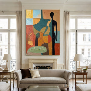 Heavy textured hand-painted abstract oil painting showcasing an elongated black figure silhouette among multi-colored blocks of terracotta, yellow, and green, hung over a wooden coffee table in a boho style living room.