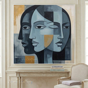 Hand-painted modern abstract cubism oil painting showing multiple overlapping geometric profiles of human faces in shades of slate blue, black, and cream white with patches of ochre gold.