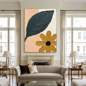 Close-up of a handmade abstract floral oil painting featuring a large heavy-textured dark green leaf and a mustard yellow flower on a blush pink and white canvas background.