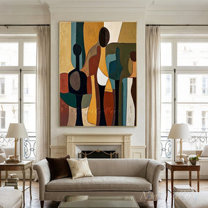 Handmade mid-century modern abstract oil painting featuring stylized people silhouettes in terracotta, mustard yellow, and emerald green with rich brush textures, hanging in a bright minimalist entryway above a dark wood console table next to a staircase.
