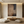Large handmade abstract oil painting in Wabi Sabi style with deep brown and black textures, styled in a minimalist zen-inspired living room above a low wooden table.