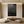 Large vertical black abstract oil painting with heavy 3D drip texture and relief strokes, hanging in a modern minimalist living room with Japanese zen furniture.