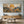 100% handmade boho mountain landscape oil painting featuring a golden sun, mountain ranges, and blooming wildflowers in warm earth tones, displayed in a modern living room setting.