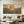 100% handmade boho desert landscape oil painting featuring a golden sun, mountains, and succulent cactus plants in warm earth tones, displayed in a modern living room setting.