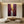 A 100% handmade abstract expressionist oil painting featuring vertical texture bands of burgundy red, crimson, and plum, with a heavily thick impasto center stripe of metallic gold and silver white paint.