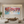 Vibrant hand-painted 3D abstract wall art featuring multicolored sculpted petals cascading down a teal and white background, displayed on a modern staircase gallery wall.