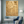 Large handmade 3D abstract canvas painting showcasing deep, heavy plaster cracked fissures filled with brilliant gold foil on a textured sandy taupe background, displayed in a minimal contemporary room interior.
