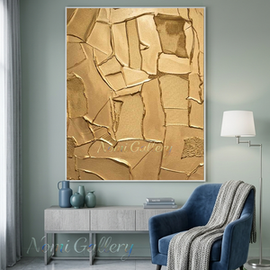 Large handmade 3D abstract canvas painting showcasing deep, heavy plaster cracked fissures filled with brilliant gold foil on a textured sandy taupe background, displayed in a minimal contemporary room interior.