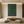 A hand-painted 3D textured oil painting in deep forest green featuring two symmetrical vertical arcs with fine rhythmic lines, creating a relief effect in a modern minimalist interior.