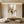 Hand-painted large abstract oil painting featuring gold leaf accents and earthy brown textures, displayed in a modern minimalist living room with warm lighting.