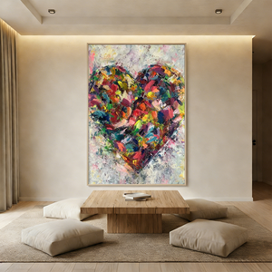 Large hand-painted abstract oil painting of a vibrant multi-colored heart with thick 3D textures, displayed in a modern zen-style living room with a low wooden table and floor cushions.