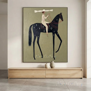 A large hand-painted abstract folk oil painting of a slender black horse and rider with a wide-brimmed hat on a textured olive green background, hung in a modern beige living room above a sofa.