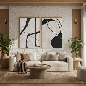 Pair of minimalist handcrafted oil paintings with thick 3D ivory texture and bold black geometric lines, styled in a boho living room with a white stone wall.