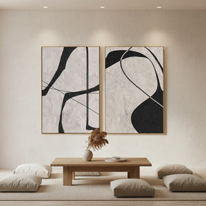 Pair of minimalist handcrafted oil paintings with thick 3D ivory texture and bold black geometric lines, styled in a boho living room with a white stone wall.