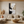 Hand-painted abstract oil painting with thick 3D impasto texture in black, white, and gold, displayed in a bright modern boho living room above a beige sectional sofa.