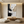 Hand-painted abstract oil painting with thick 3D impasto texture in black, white, and gold, displayed in a bright modern boho living room above a beige sectional sofa.