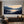 Detailed view of a hand-painted impressionist oil painting depicting a tranquil Highland Lake with deep blue foreground reeds and a warm peach and yellow sunset.