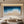 Close-up of a 100% hand-painted abstract oil painting showcasing thick 3D textured impasto ocean waves in deep blue and white crashing onto a sandy beige shoreline.