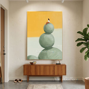 Hand-painted minimalist oil painting featuring a woman in a terracotta dress sitting on top of three stacked round green stones against a bright yellow background.