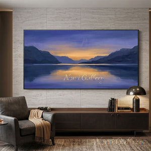 A 100% hand-painted impressionist landscape oil painting featuring deep purple and blue mountains flanking a calm lake that reflects a warm golden sunset sky.