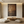 Hand-painted Wabi-Sabi abstract oil painting with heavy texture in deep brown, sienna, and charcoal tones, displayed in a minimalist boho living room setting.