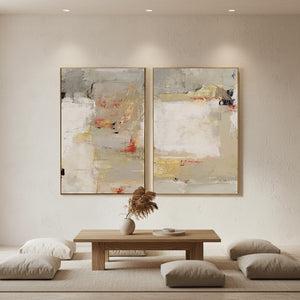 Pair of hand-painted Wabi-Sabi abstract oil paintings featuring heavy impasto texture in beige, grey, and earthy red tones, displayed over a minimalist wooden table in a Zen-style living room.