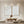 Set of two hand-painted white minimalist abstract paintings featuring heavy 3D impasto texture with wave-like patterns, displayed in a serene Zen-style living room setting.