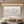 Large handmade white oil painting of a mountain range with heavy 3D impasto texture, displayed in a modern minimalist living room setting with warm cove lighting and neutral decor.