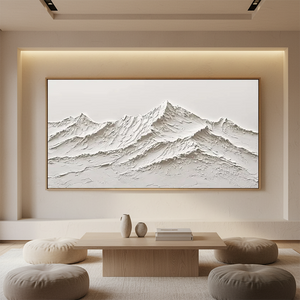 Large handmade white oil painting of a mountain range with heavy 3D impasto texture, displayed in a modern minimalist living room setting with warm cove lighting and neutral decor.