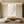 Hand-painted 3D textured white flower oil painting with thick impasto petals, displayed in a bright boho living room above a cream-colored sofa.