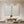 Pair of hand-painted white abstract paintings with heavy diagonal 3D impasto brushstrokes, shown in a modern minimalist living room featuring a wooden table and low seating.