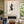 Hand-painted abstract oil painting with fluid black looping lines and a textured smoky black central geometric shape, showcased on a gallery wall above a modern fireplace in a luxury living room.