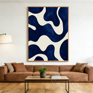 Large hand-painted abstract oil painting with minimalist organic fluid shapes in deep indigo blue and warm cream, displayed above a low wooden table in a relaxing boho style living room.