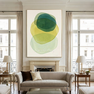Large hand-painted abstract oil painting with translucent, overlapping organic geometric shapes in forest green, mustard yellow, and mint green, hung beautifully over a classic fireplace in a bright modern living room.