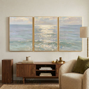 100% handmade abstract sea landscape oil painting featuring a triptych design of tranquil ocean waves and a shimmering sea in blue and neutral earth tones, displayed in a modern living room setting.