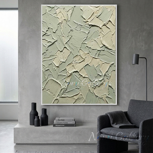 Handmade large 3D heavy textured abstract oil painting in calming sage green and cream tones with prominent palette knife strokes, hanging on a white minimalist gallery wall next to a modern staircase and a lounge armchair.