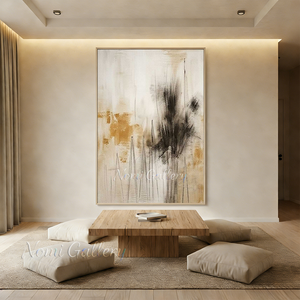 Original handmade Japandi style abstract oil painting featuring warm ochre washes and charcoal black brushstrokes resembling misty trees, displayed on a beige plaster wall in a modern minimalist living room above a low wooden coffee table with floor cushions.