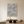 Large hand-painted 3D textured beige abstract oil painting with organic concentric swirls, hanging above a dark wood table in a warm minimalist room.