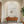 Large original handmade 3D heavy textured minimalist oil painting in plaster off-white, featuring a unique hollowed-out circle revealing natural sandy beige tones, styled on a warm beige plaster wall in an upscale Japandi living room above a low wooden coffee table.