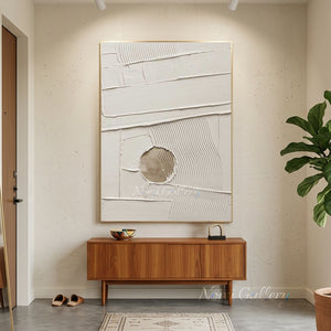 Large original handmade 3D heavy textured minimalist oil painting in plaster off-white, featuring a unique hollowed-out circle revealing natural sandy beige tones, styled on a warm beige plaster wall in an upscale Japandi living room above a low wooden coffee table.