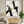 Large original handmade modern abstract oil painting featuring cascading metallic gold leaf over sweeping charcoal black ink washes, beautifully displayed on a white wall in a luxury contemporary living room behind a neutral modern sofa.