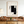 Large original handmade minimalist black and white abstract oil painting featuring sweeping charcoal lines on a pure white canvas, displayed on a gallery wall next to a modern black iron frame staircase.