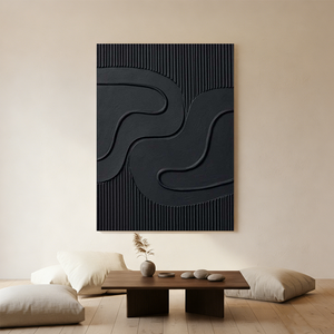 Large hand-painted 3D textured black abstract oil painting with two concentric swirl patterns, hanging in a modern minimalist living room with a black armchair.