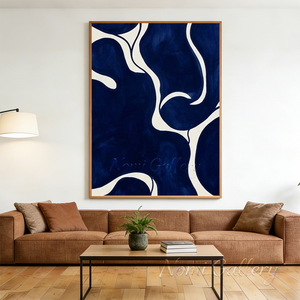 Large handmade abstract oil painting with fluid, deep cobalt blue organic shapes and winding white lines, framed in natural wood and displayed in a minimalist Japandi living room above a low wooden tea table with floor cushions.