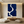 Large handmade abstract oil painting featuring massive organic fluid shapes of deep navy blue divided by flowing ivory white paths, enclosed in a black frame on a minimalist gallery staircase wall above a modern white credenza.