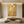 Large handmade 3D abstract canvas painting showcasing elegant fluid metallic gold lines curving across a heavy white plaster textured background, framed in black and styled on a warm minimalist living room wall above a beige sofa.