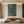 A hand-painted 3D textured oil painting in deep forest green featuring a labyrinthine pattern of interlacing straight lines and circular curves, creating a rich relief effect in a modern Zen-style room.