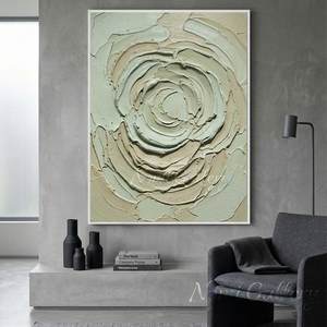 Handmade 3D textured oil painting featuring a swirling abstract green and cream flower, hanging on a concrete wall in a modern living room with a grey armchair.