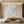 A hand-painted minimalist oil painting depicting abstract mountain peaks with a heavy 3D textured foreground in beige and dark gray, styled in a contemporary neutral living room.